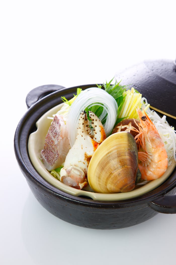 Delicious seafood hot pot featuring clams, shrimp, vegetables in a ceramic bowl.